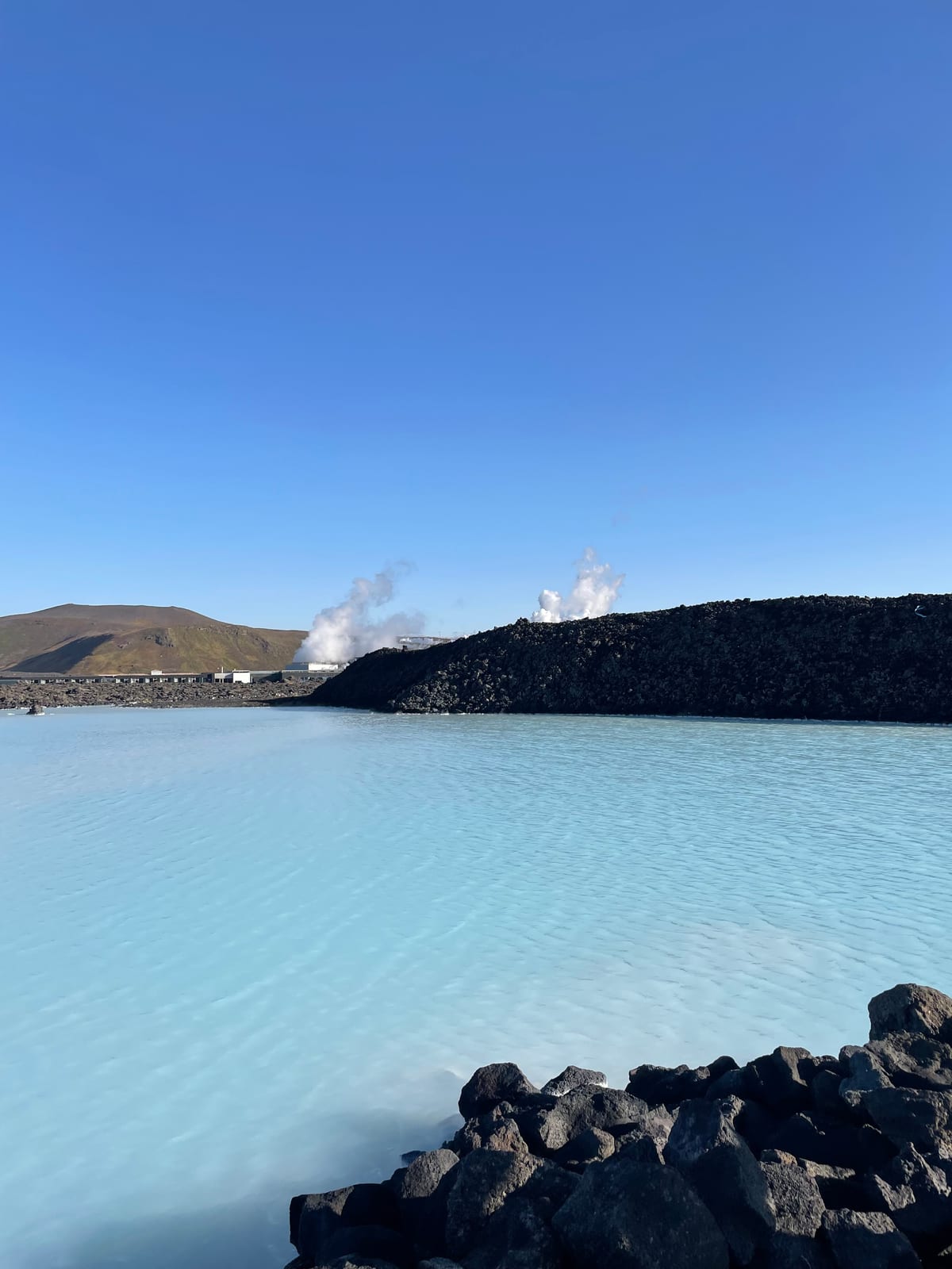 Milky-blue geothermal water against black lava rock at the Blue Lagoon