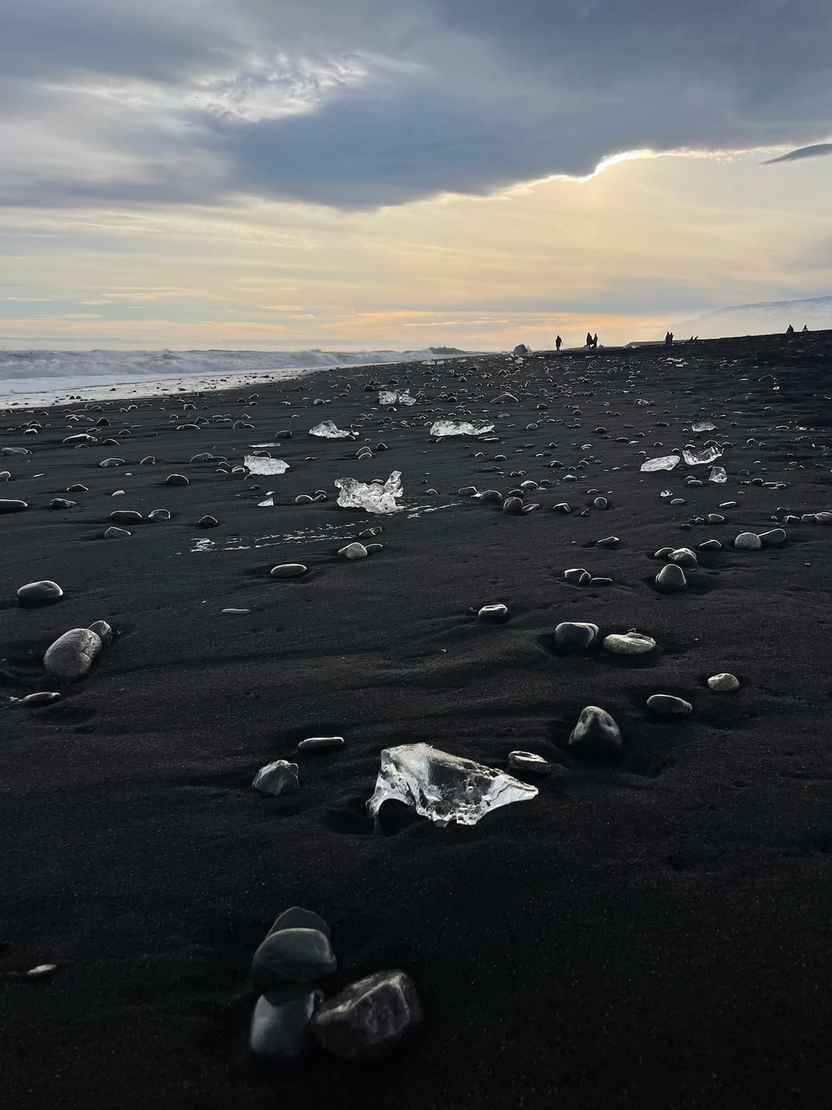 A clear block of glacier ice glowing on the black sand at Diamond Beach