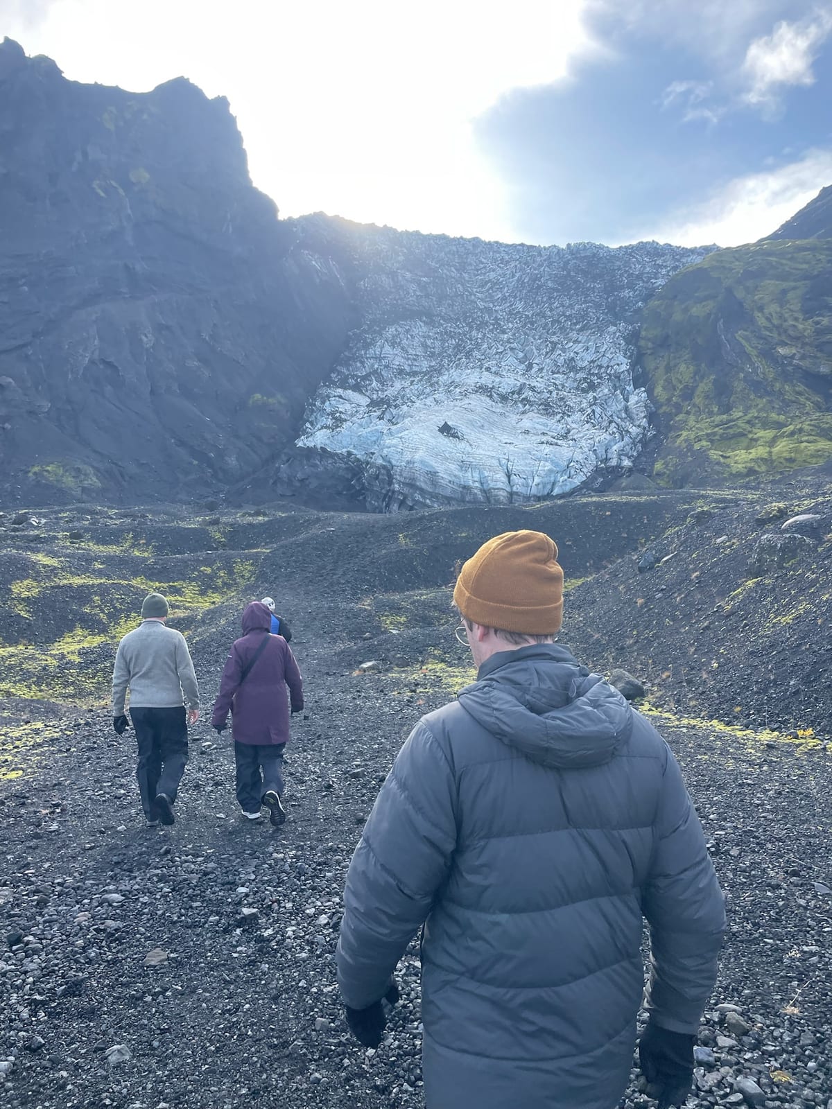 A traveler walking across black glacial till toward the Eyjafjallajokull glacier