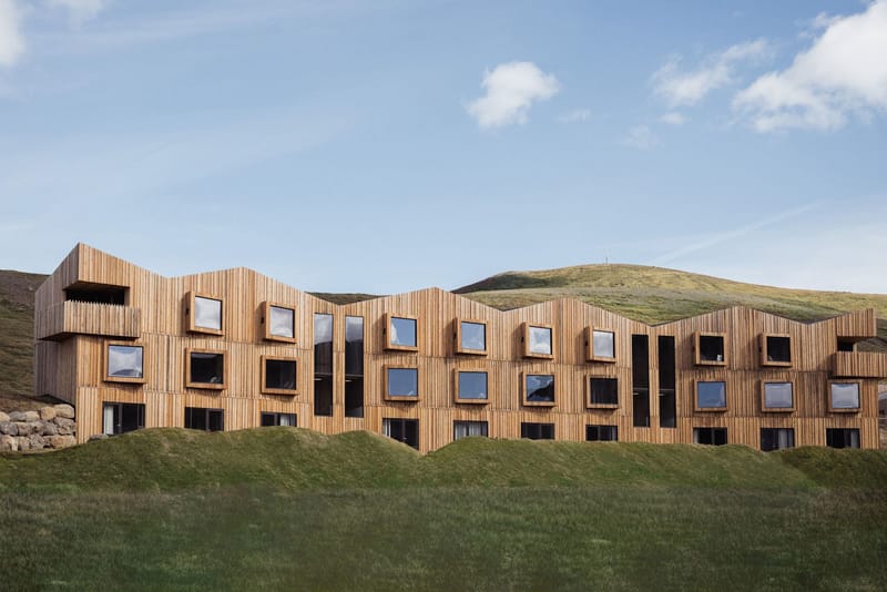 The timber-clad Highland Base lodge below green highland slopes