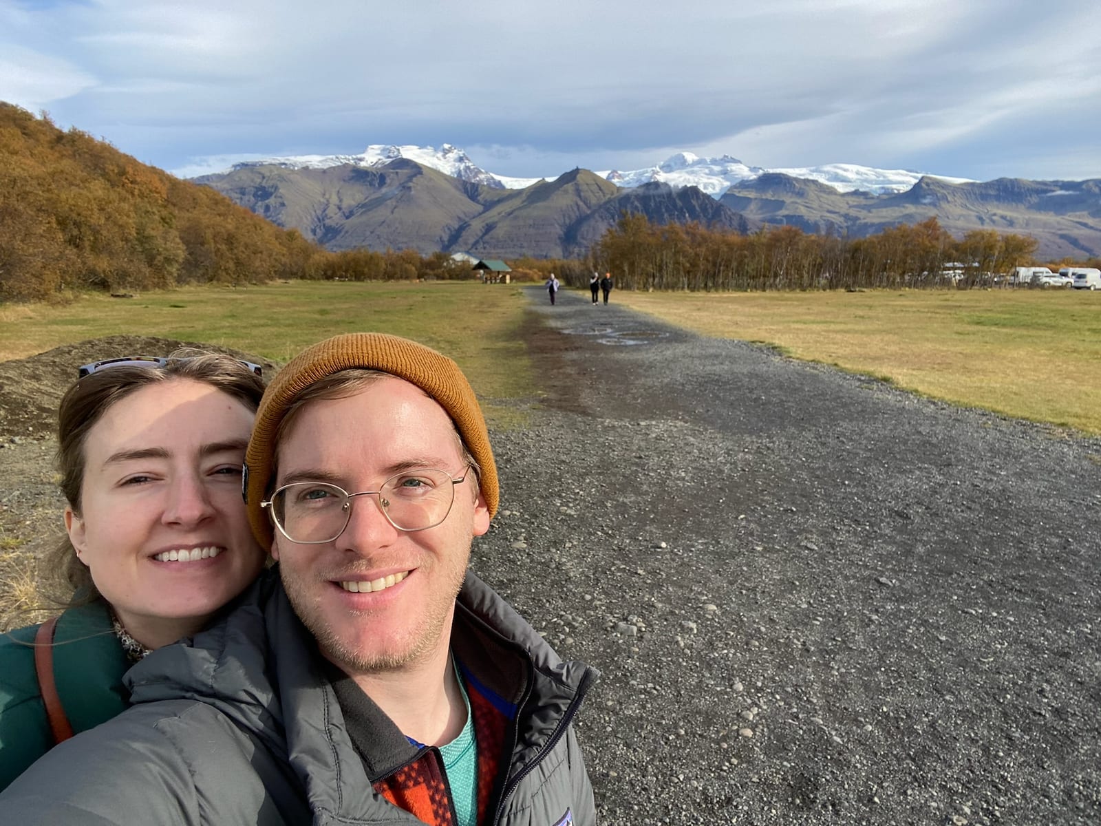 Two hikers on the Skaftafell trail with autumn mountains behind