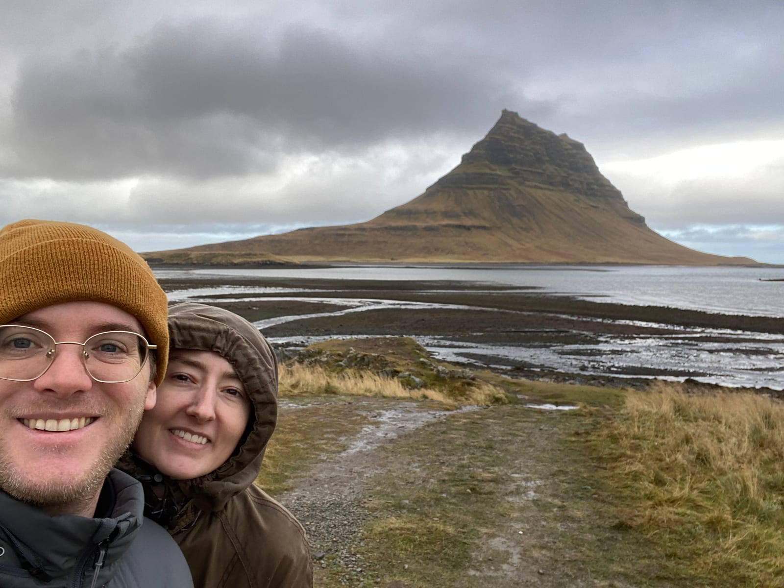 Two travelers below the pointed Kirkjufell mountain on the Snaefellsnes coast