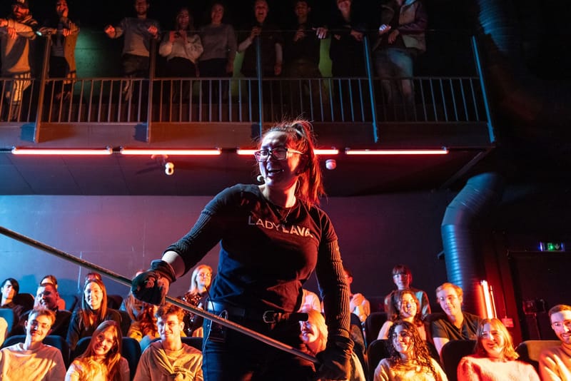 A Lava Show presenter on stage in red light before the audience