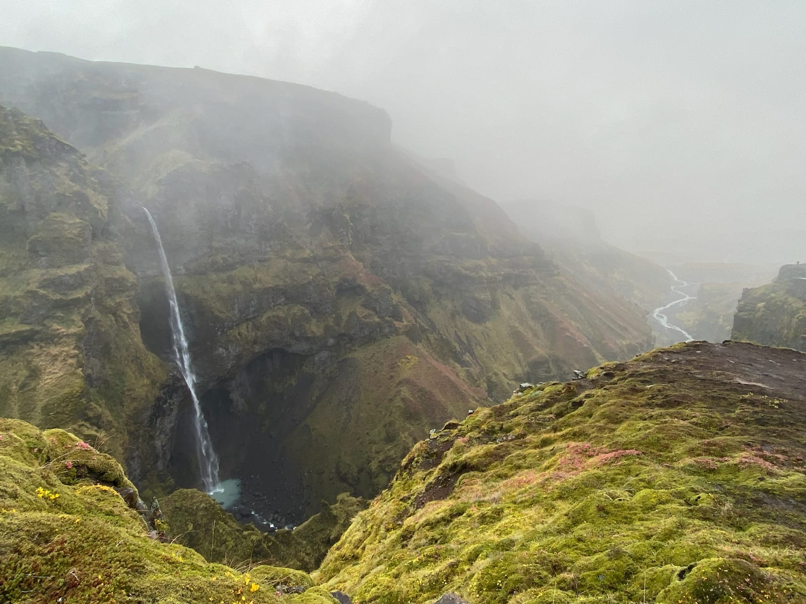 Two hikers on the mossy rim of Mulagljufur canyon