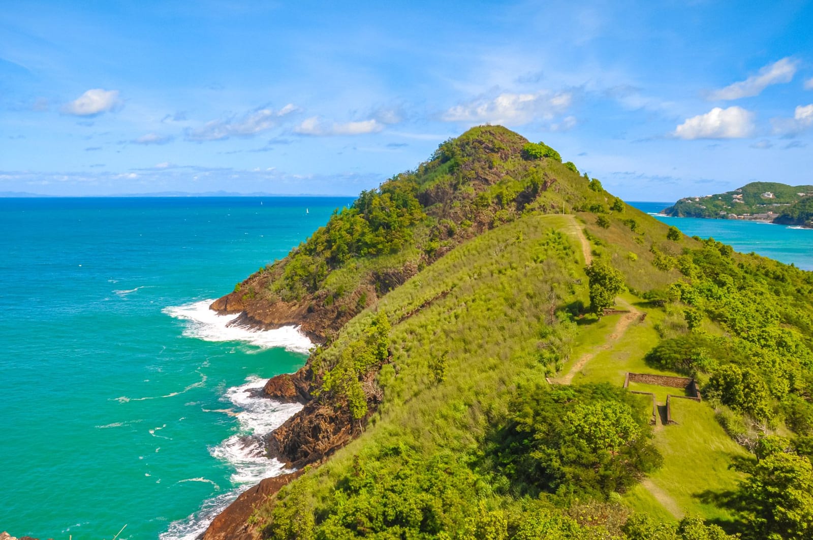 The green headland of Pigeon Island dropping to turquoise sea