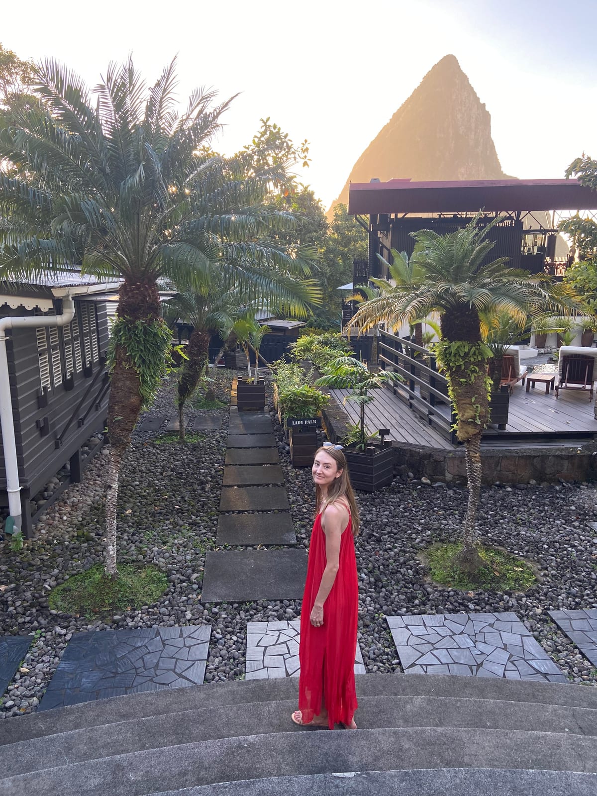 A guest on the estate steps at golden hour with a Piton rising behind