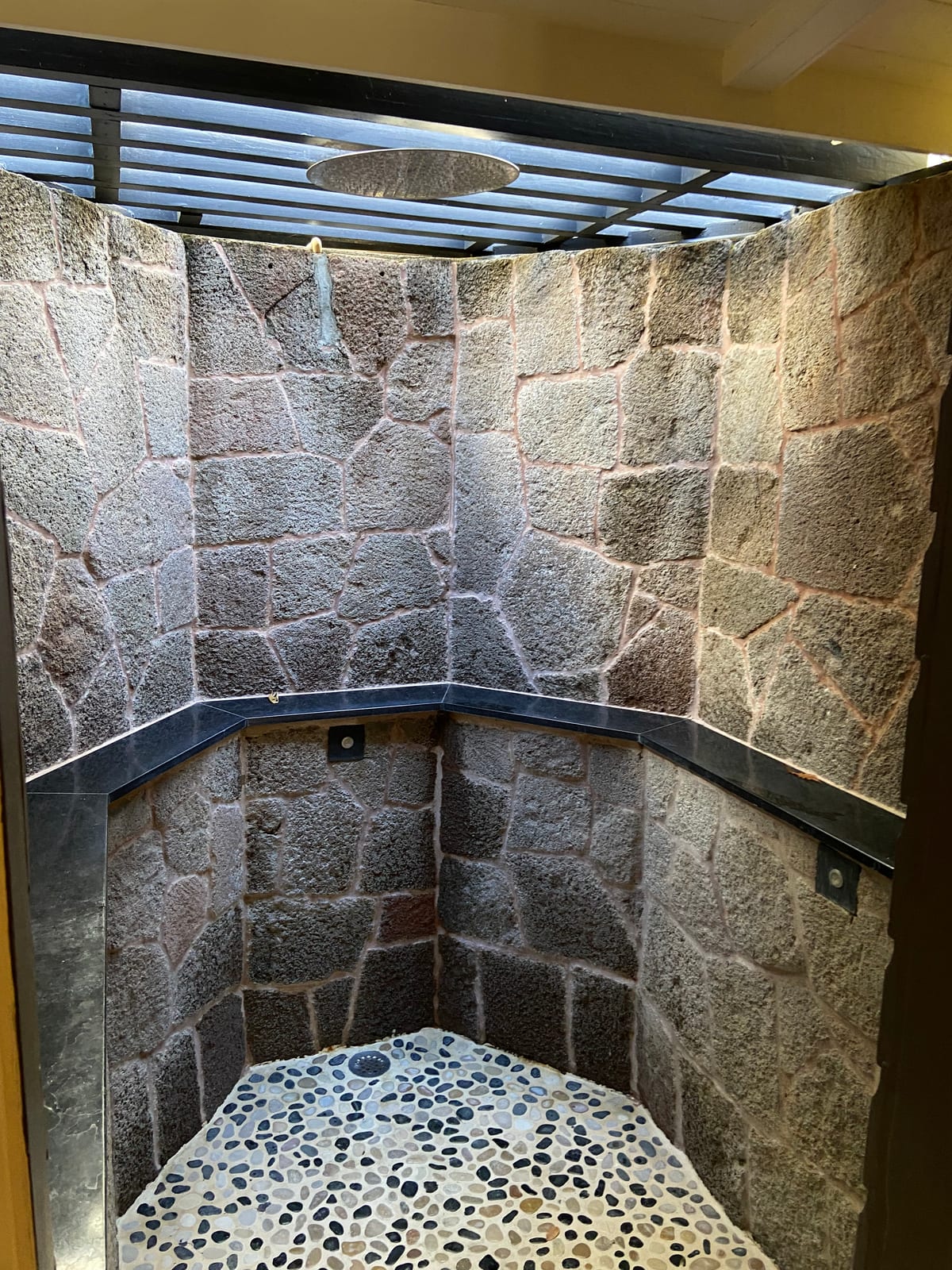 A stone-walled outdoor shower with a rain head