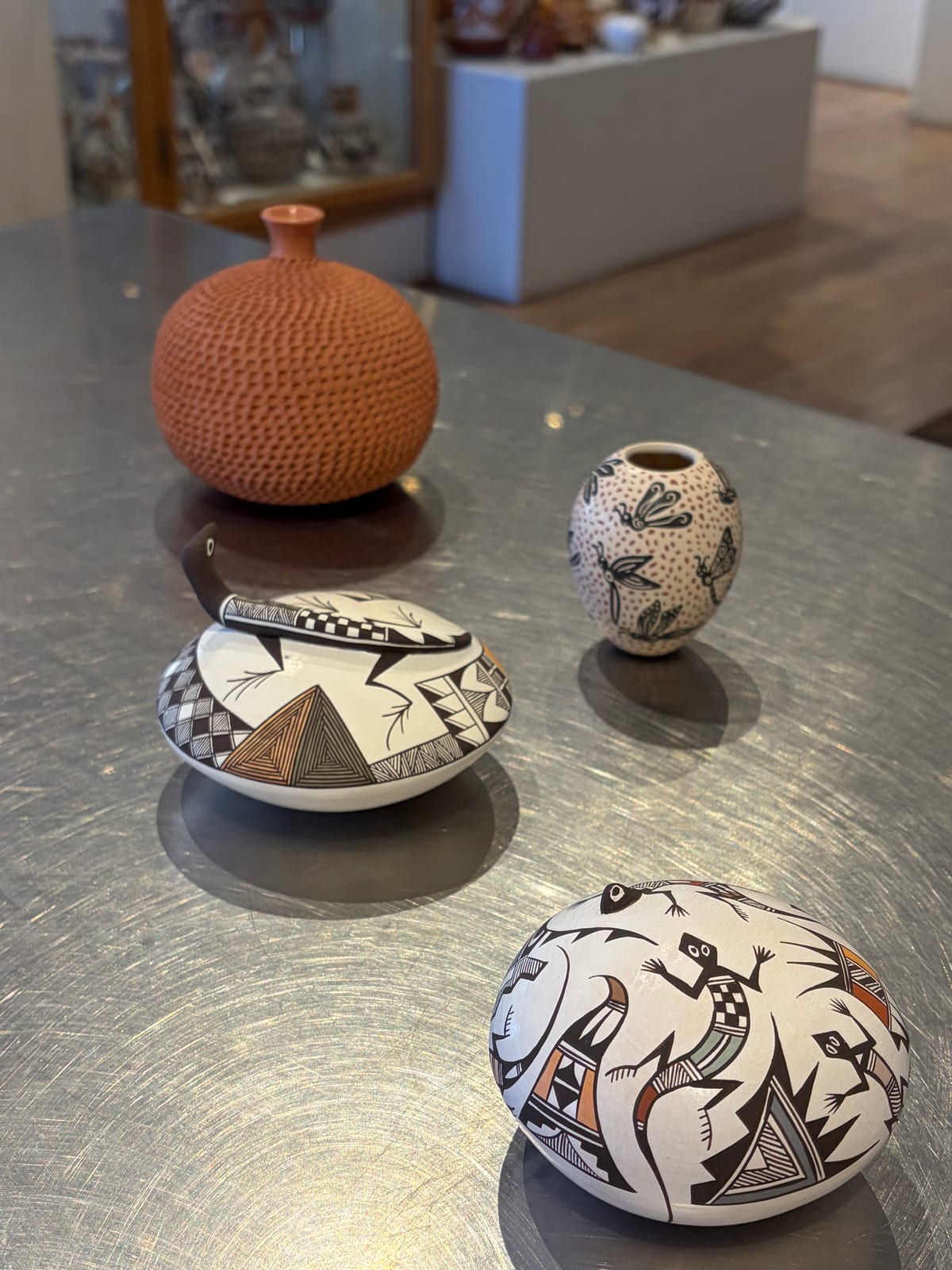Four hand-painted Pueblo pots on a steel table at Andrea Fisher Fine Pottery