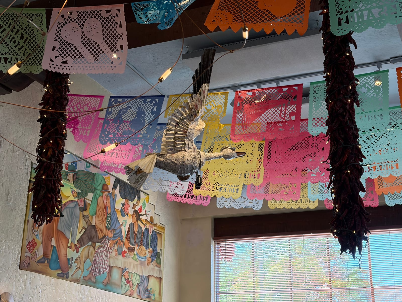 Papel picado banners, chile ristras and a folk mural on the ceiling at Cafe Pasqual's