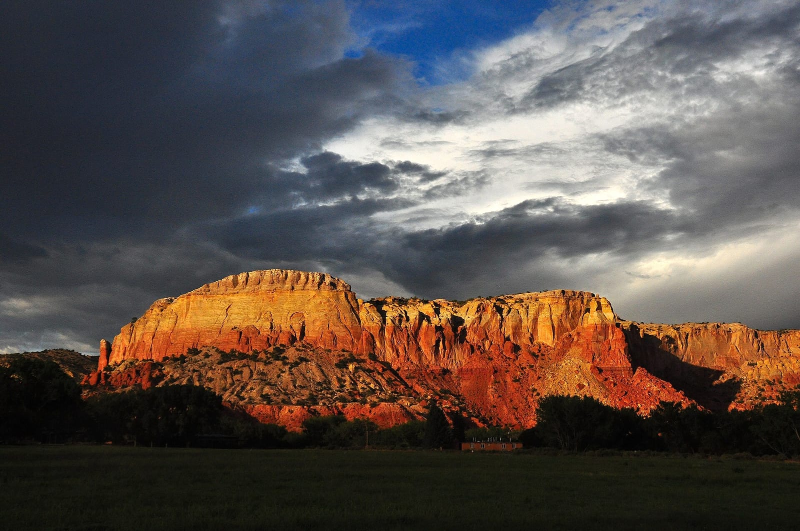 The banded red rock cliffs at Ghost Ranch under building cloud