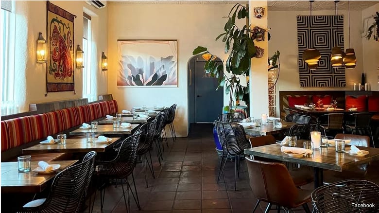The dining room at Paloma in Santa Fe, with striped banquettes, woven chairs and a tiled floor