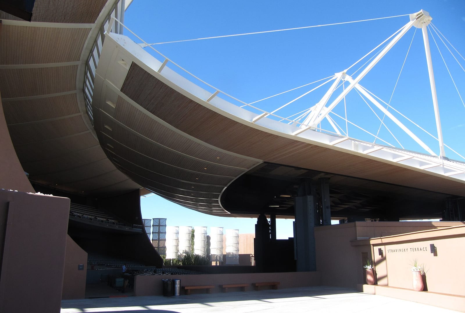 The sweeping cantilevered roof and open sides of the Crosby Theatre at the Santa Fe Opera against a blue sky