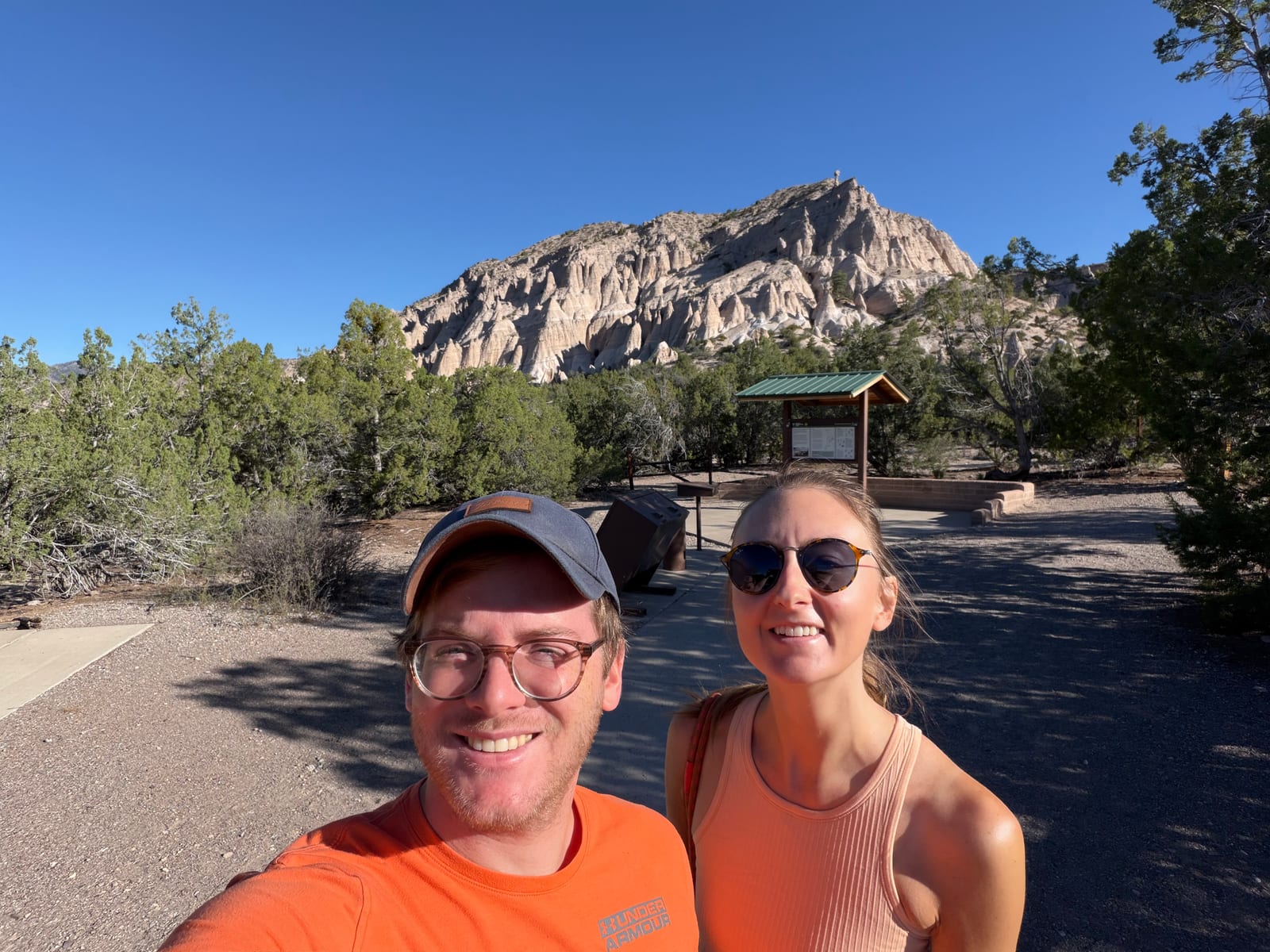 Two visitors at the Tent Rocks trailhead with the formation behind