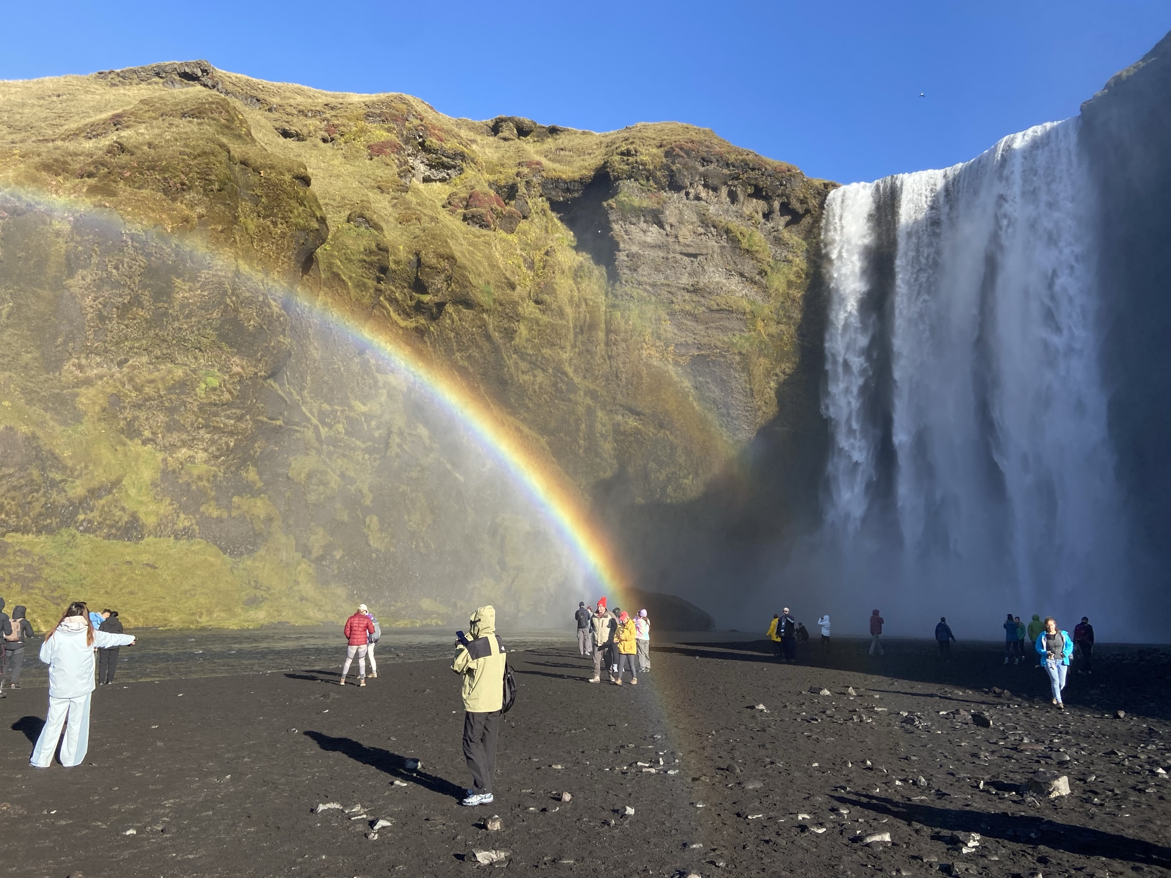 A rainbow arcing through the spray at the foot of Skogafoss waterfall