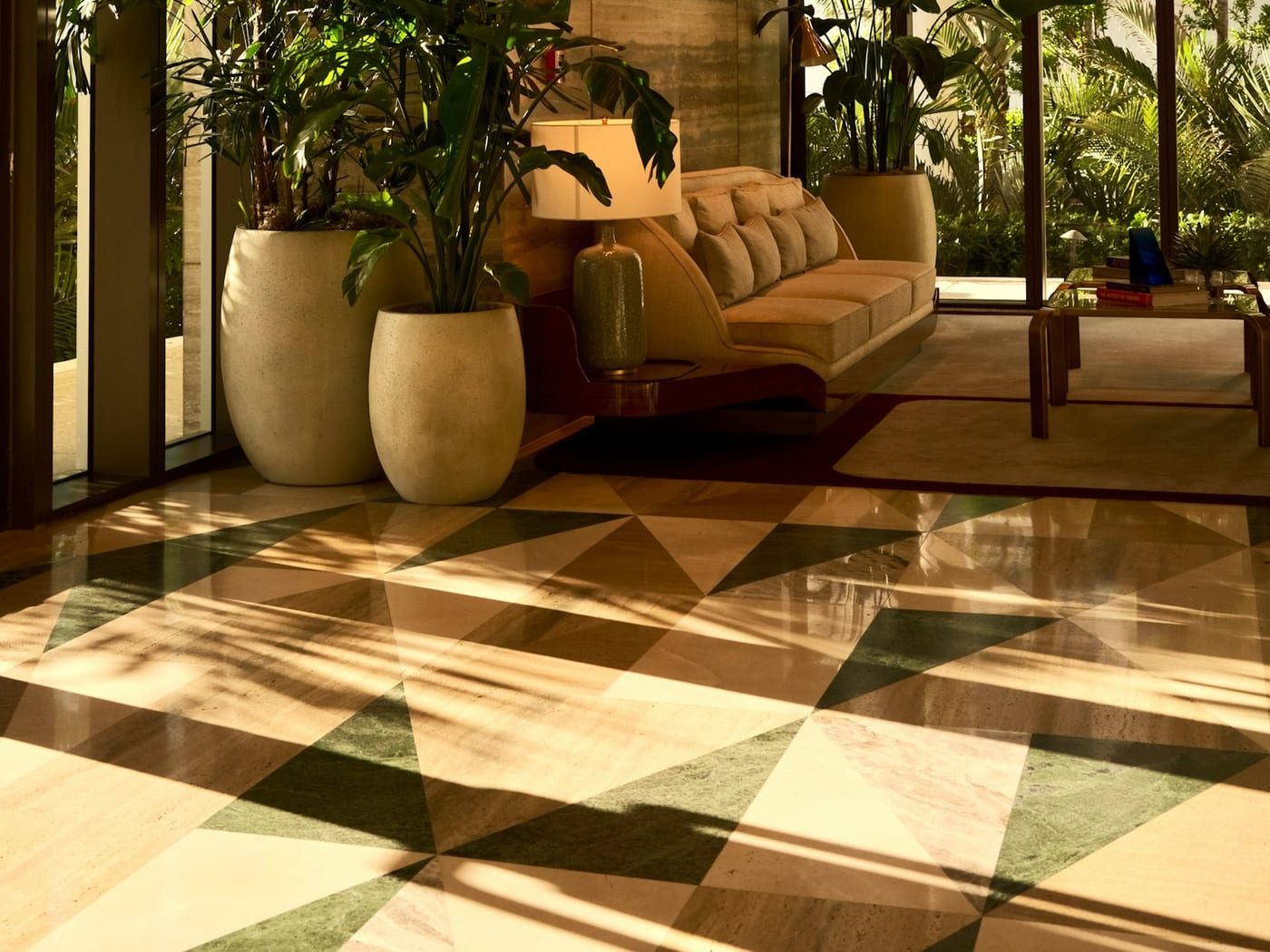 A sunlit lobby of travertine and palms above a patterned marble floor
